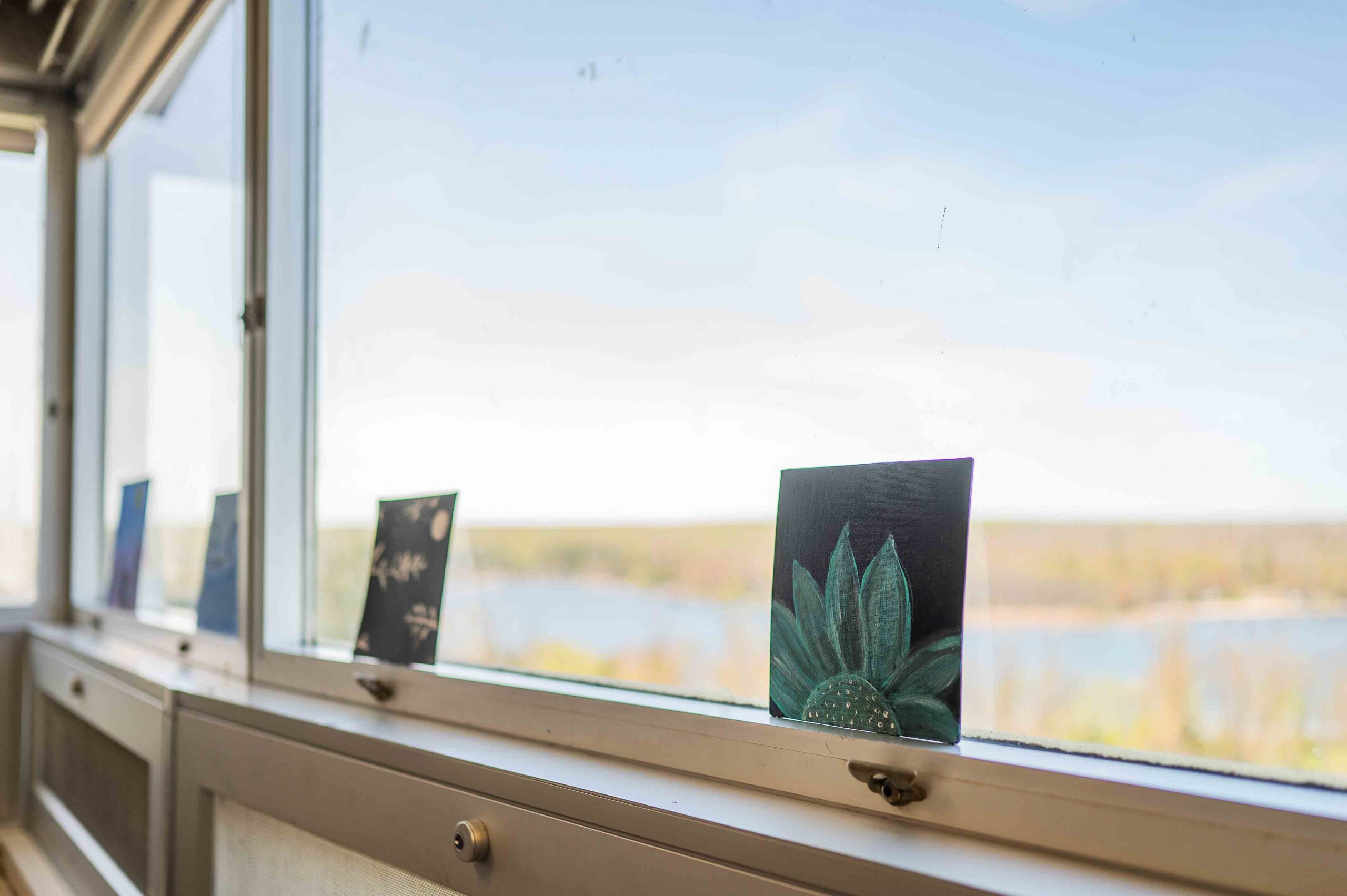 Paintings of flowers and greenery lean against large windows in a mental health centre.