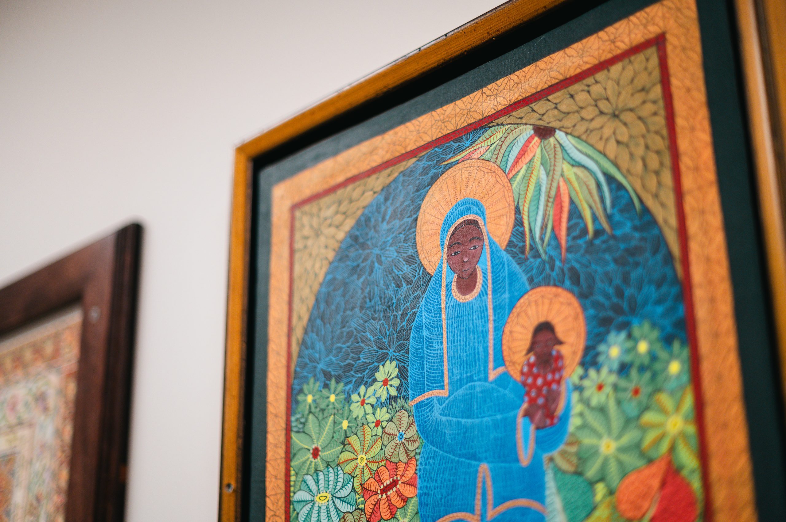 A framed painting hanging on the wall in the hallway which depicts a woman and baby.