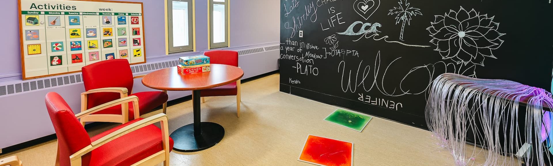 A calming room within the Horizons program with red chairs and a chalk board wall.