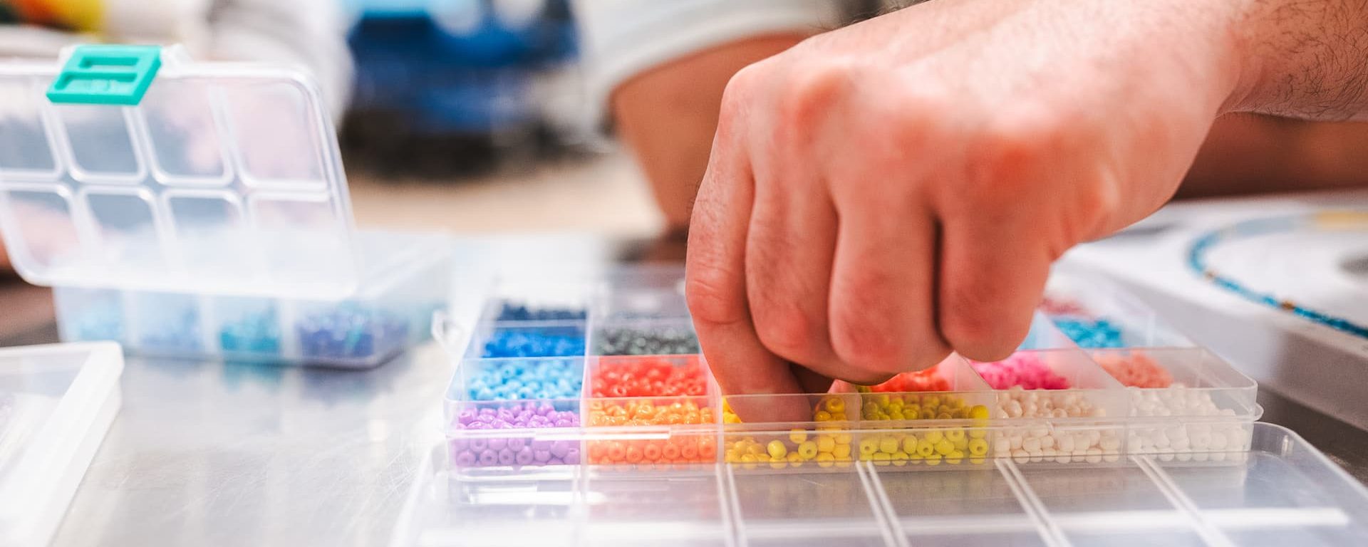 A person reaching into an organized container of colour beads during a patient program.