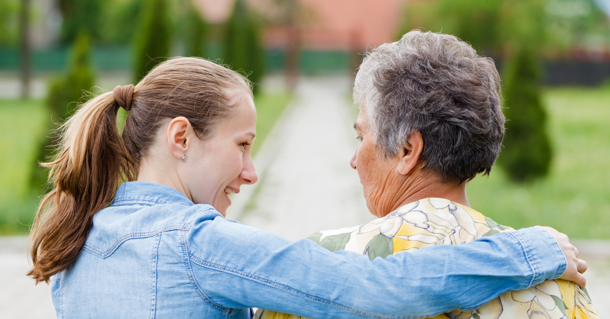 Two women, seen from behind, walking forward in each others' arms.