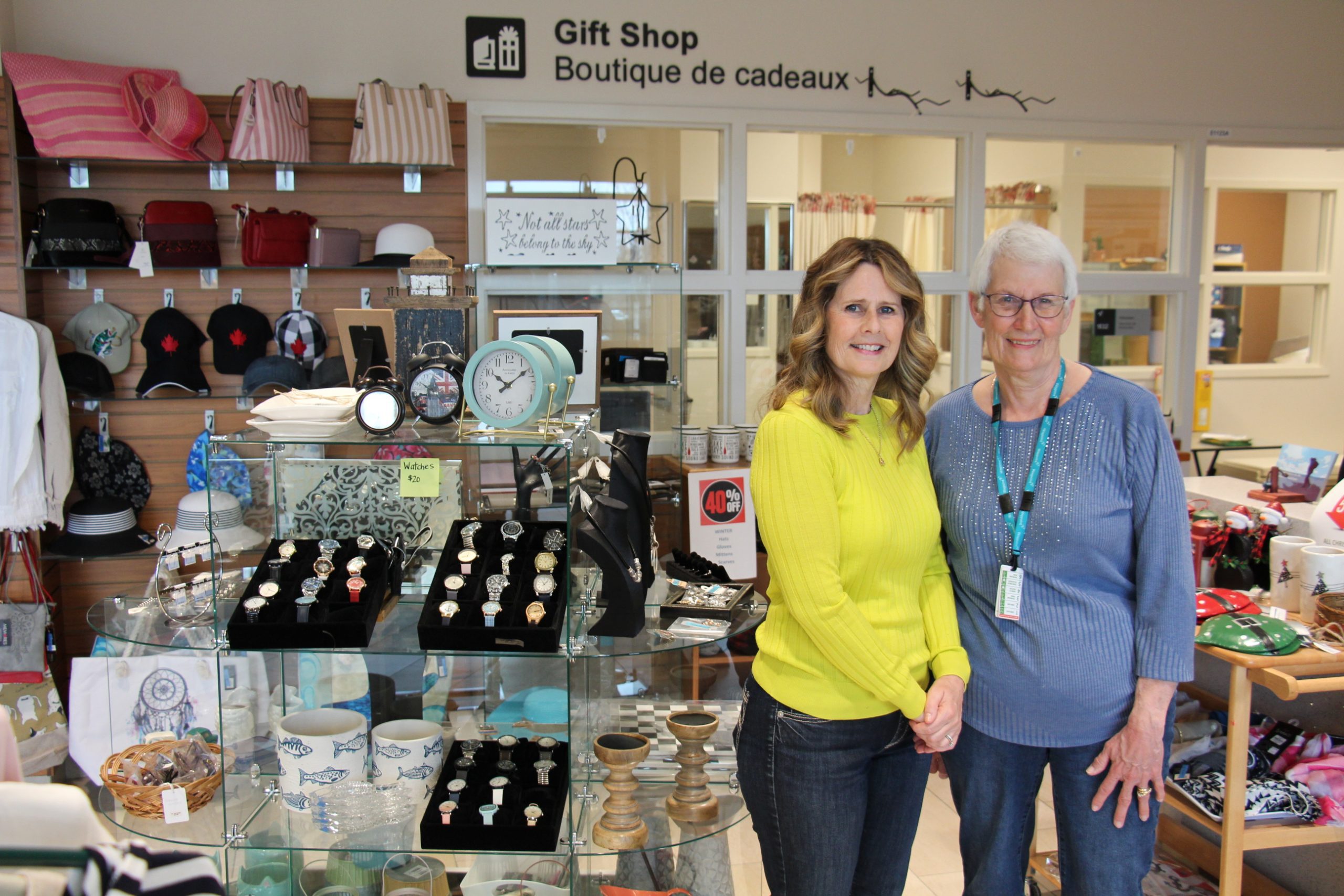 Two volunteers stand in front of the Waypoint Gift Shop.