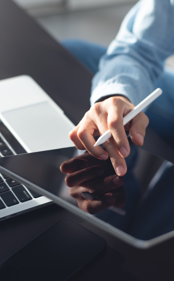 A person sits at a table holding a tablet and stylus pen.