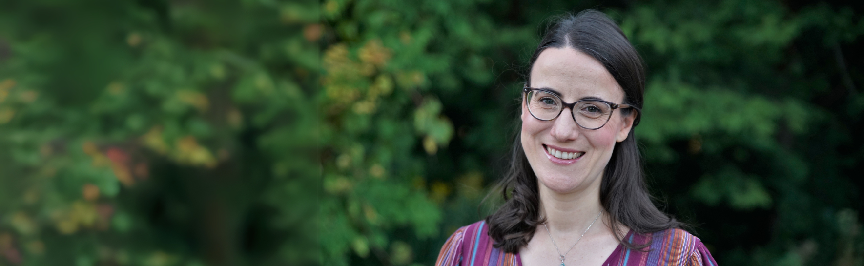 Kelly Lefaive standing in front of green trees smiling